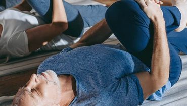 Older man stretching in a yoga class.