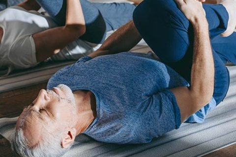 Older man stretching in a yoga class.