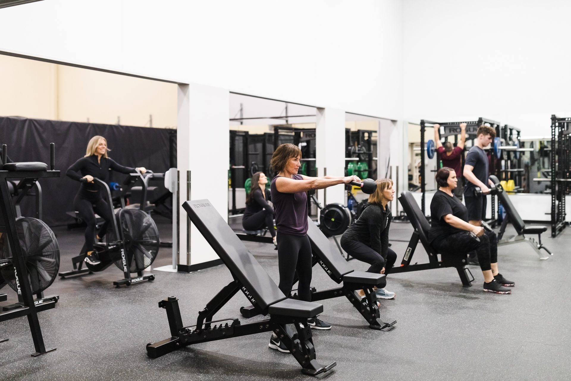 A group of members and personal trainers using the Free Weight Room at Airport Health Club